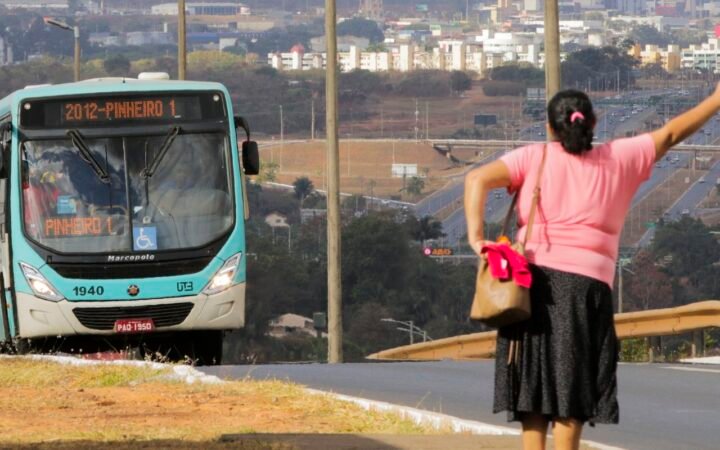 Mulher acena para um ônibus em via de Águas Claras, no Distrito Federal.