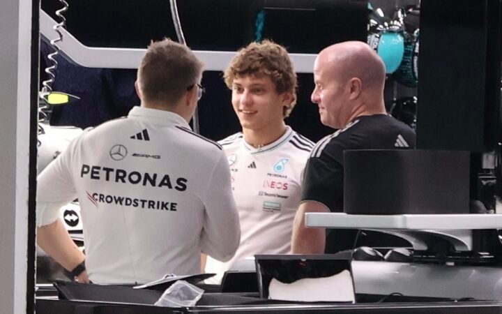Kimi Antonelli ao centro da garagem da Mercedes, entre dois integrantes da equipe, em foto de arquivo do GP de Singapura de 2 de outubro de 2025.