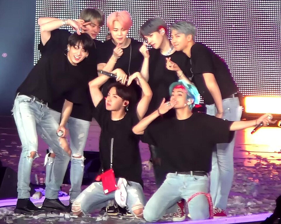 Integrantes do BTS reunidos no palco de uma apresentação de arquivo.