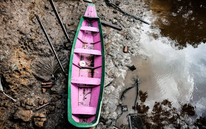 Pequeno barco de madeira verde e rosa junto à margem de um rio na Ilha do Combu, em Belém, em 2017.