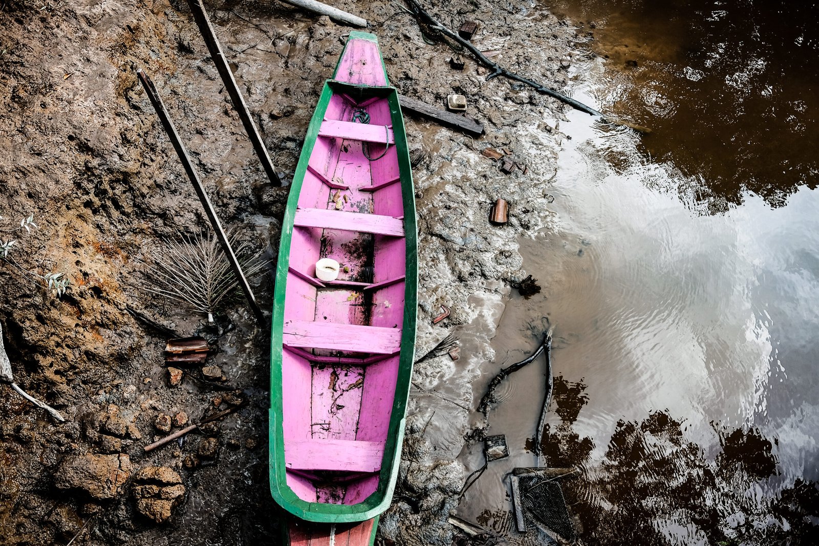 Pequeno barco de madeira verde e rosa junto à margem de um rio na Ilha do Combu, em Belém, em 2017.
