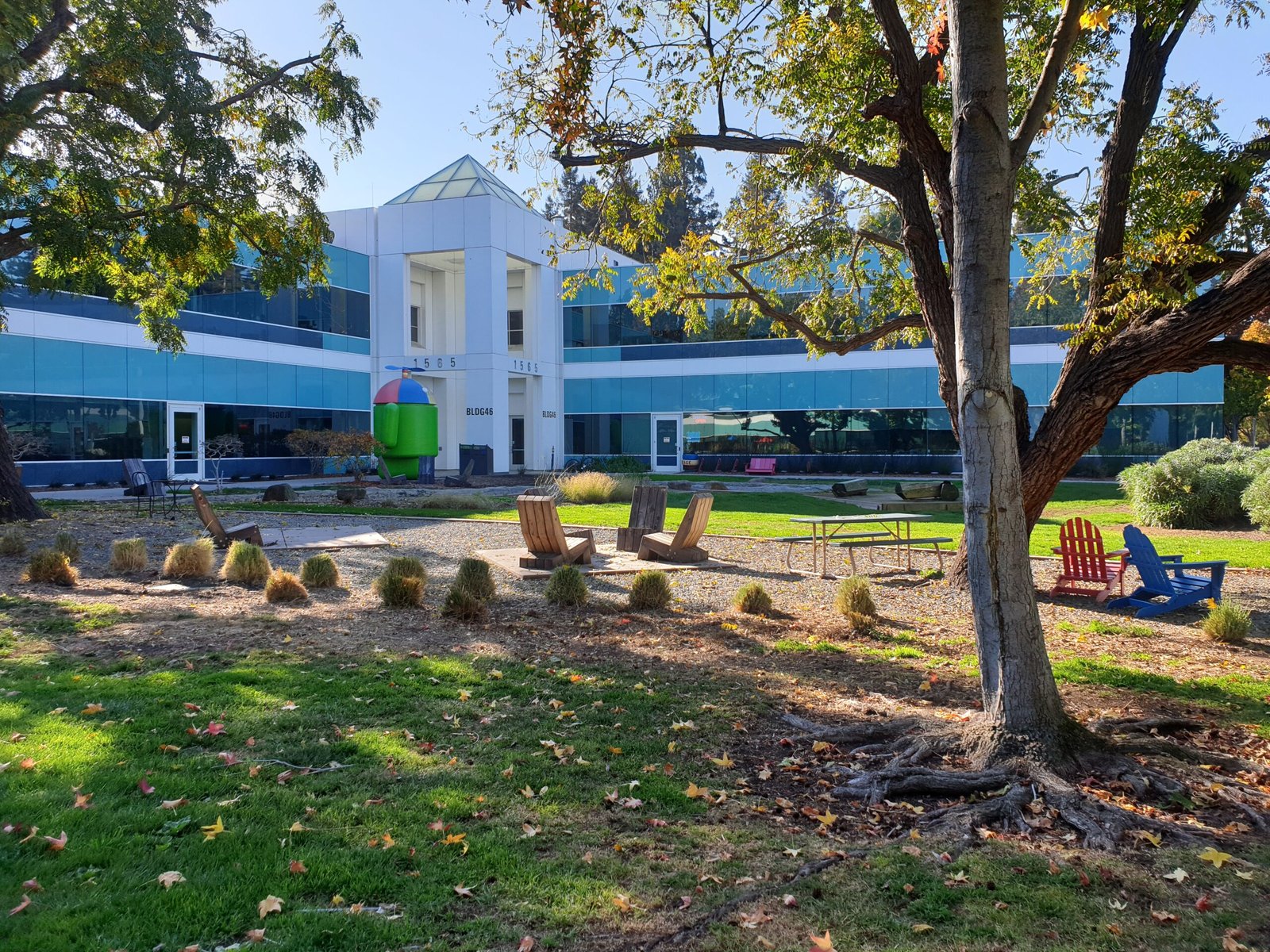 Área externa colorida do Googleplex, em Mountain View, fotografada em 17 de novembro de 2019. Prédio com vidraças, árvores e cadeiras; imagem de arquivo de Misaochan2.