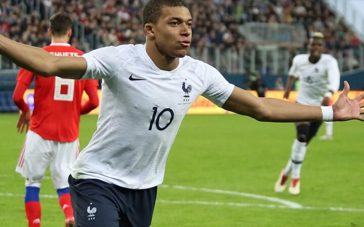Mbappé com uniforme branco da França, em campo, em março de 2018.
