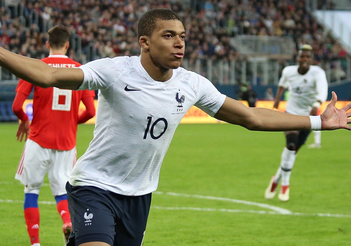 Mbappé com uniforme branco da França, em campo, em março de 2018.