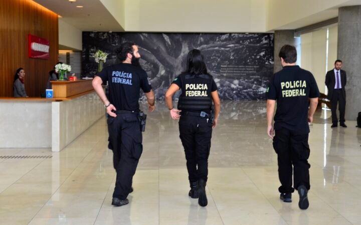 Três agentes da Polícia Federal de costas no saguão da sede da Odebrecht, em foto de arquivo de 2016.