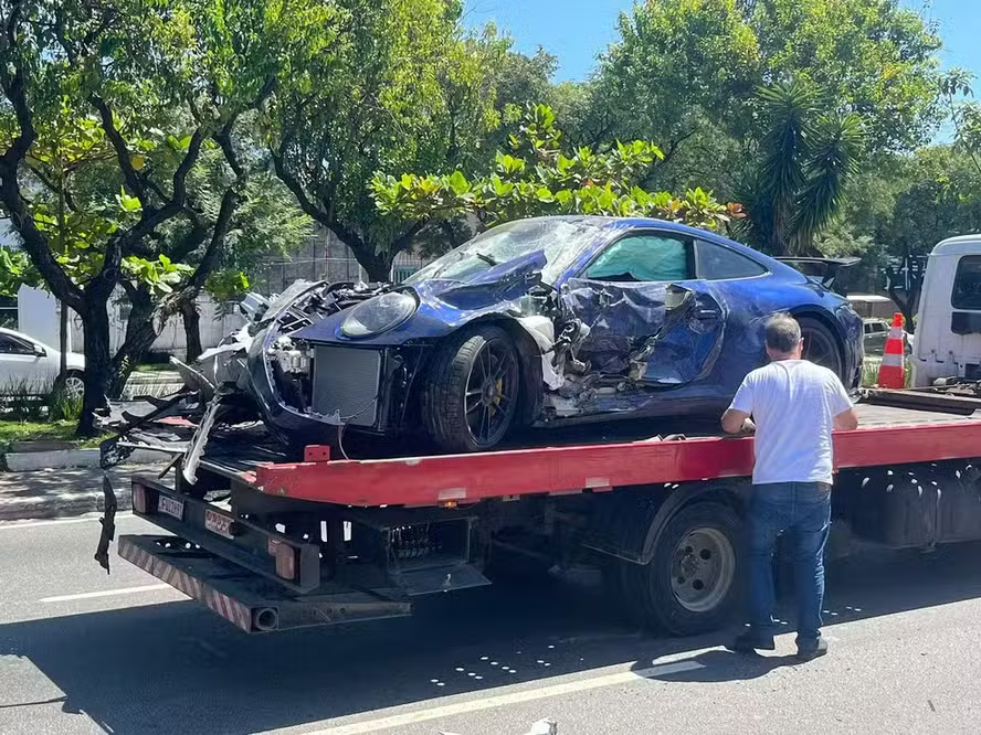 Carro esportivo azul com a dianteira danificada sobre um guincho.