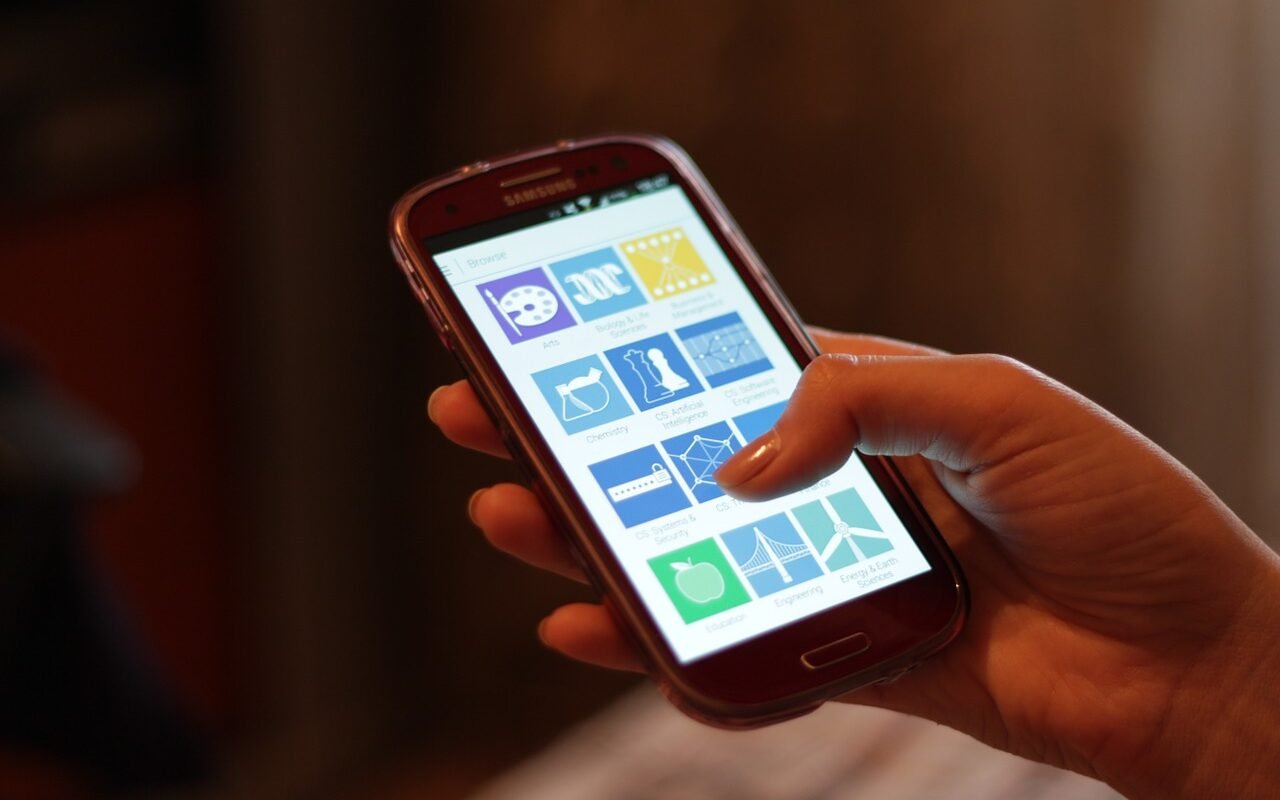 Mão segura um celular com aplicativos na tela