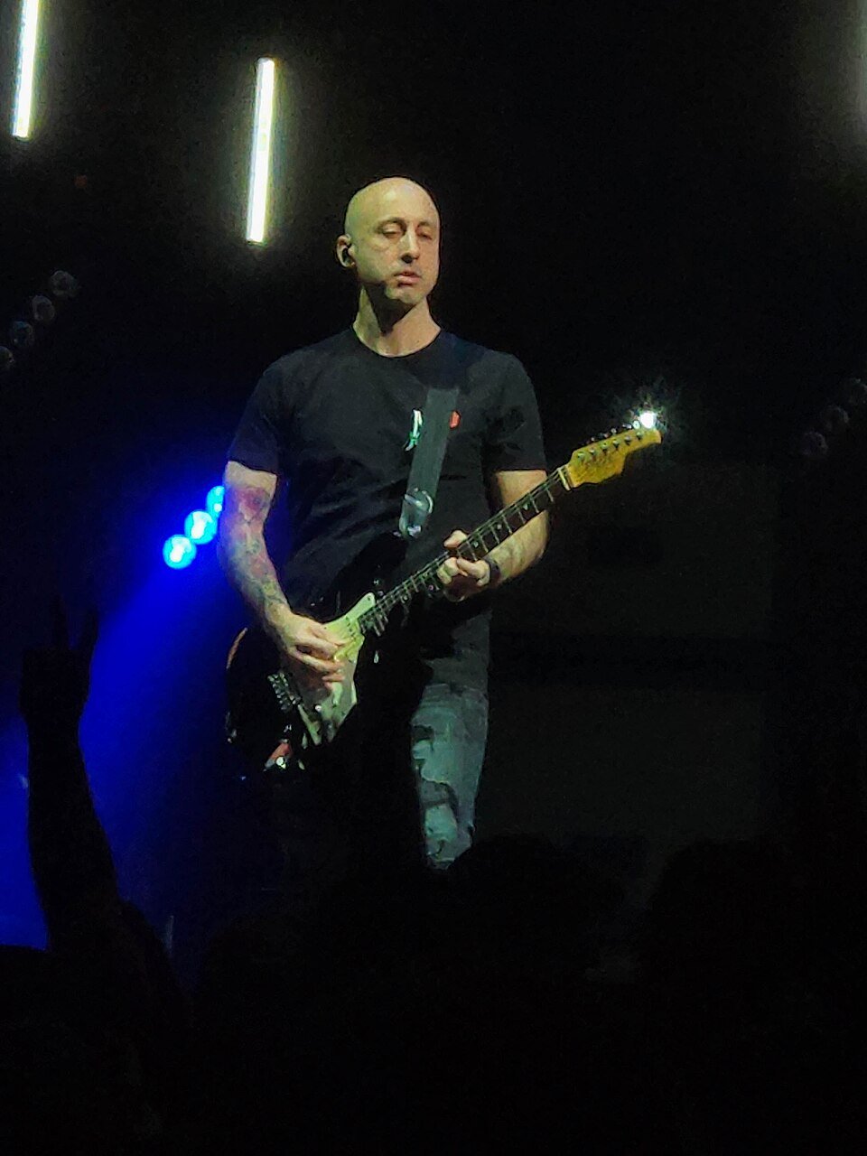 Músico do Simple Plan toca guitarra no palco de um show de arquivo.