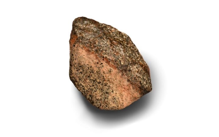 Meteorito Teghaza 001, com superfície rosada e minerais escuros, sobre fundo branco, em foto de divulgação do estudo de 29 de outubro de 2026.