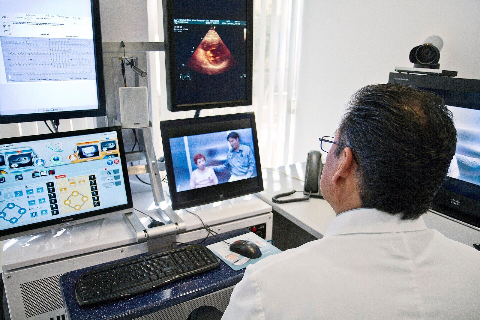 Profissional de saúde diante de monitores em demonstração de telemedicina de 2011.