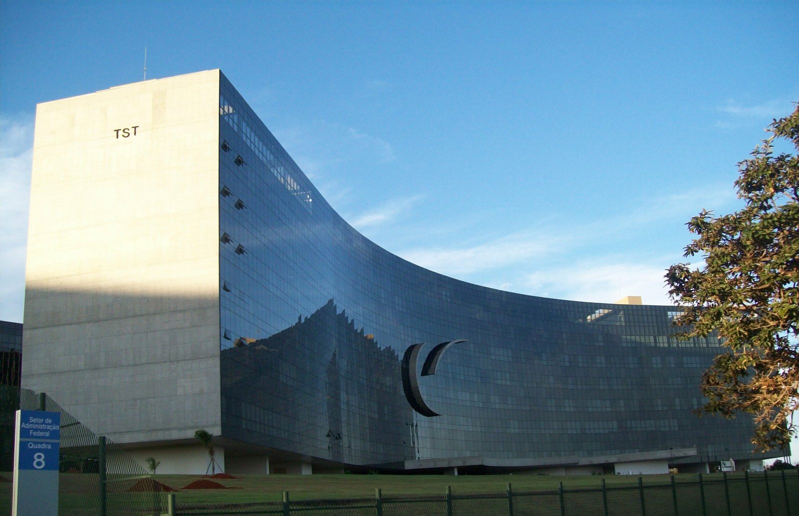 Fachada do Tribunal Superior do Trabalho, em Brasília, com paredes claras e vidros azuis.