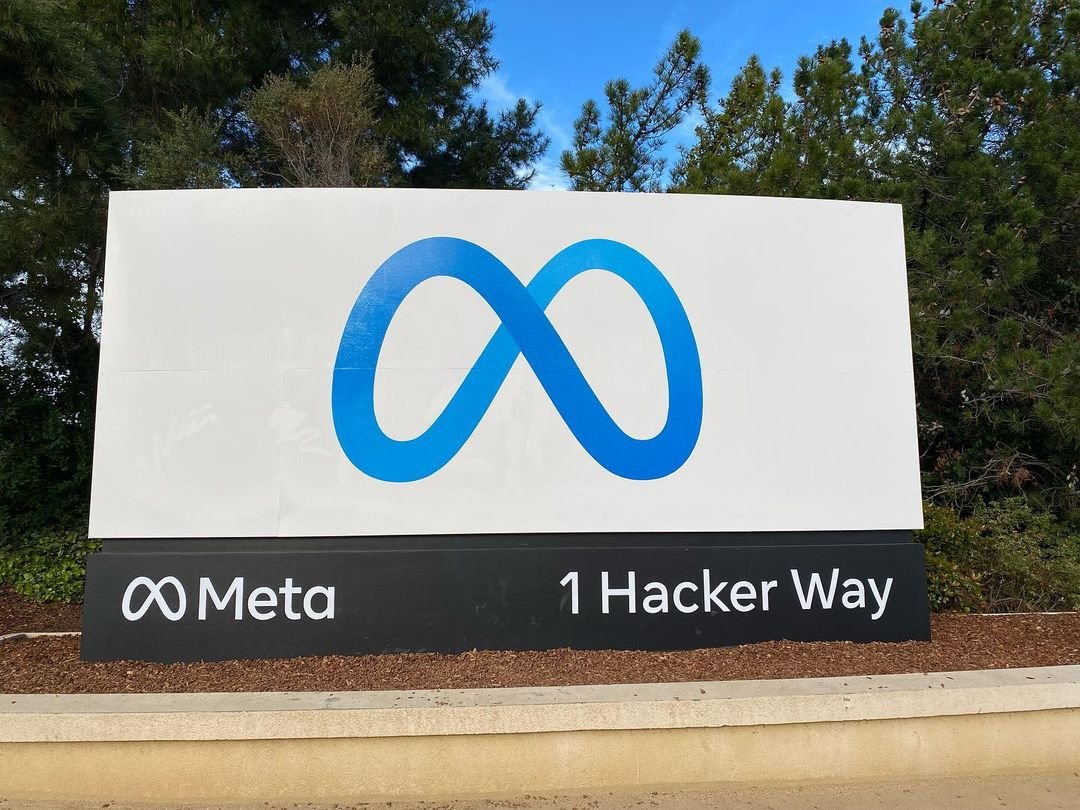 Placa com o logotipo azul da Meta em primeiro plano e o nome Meta na base, em Menlo Park.