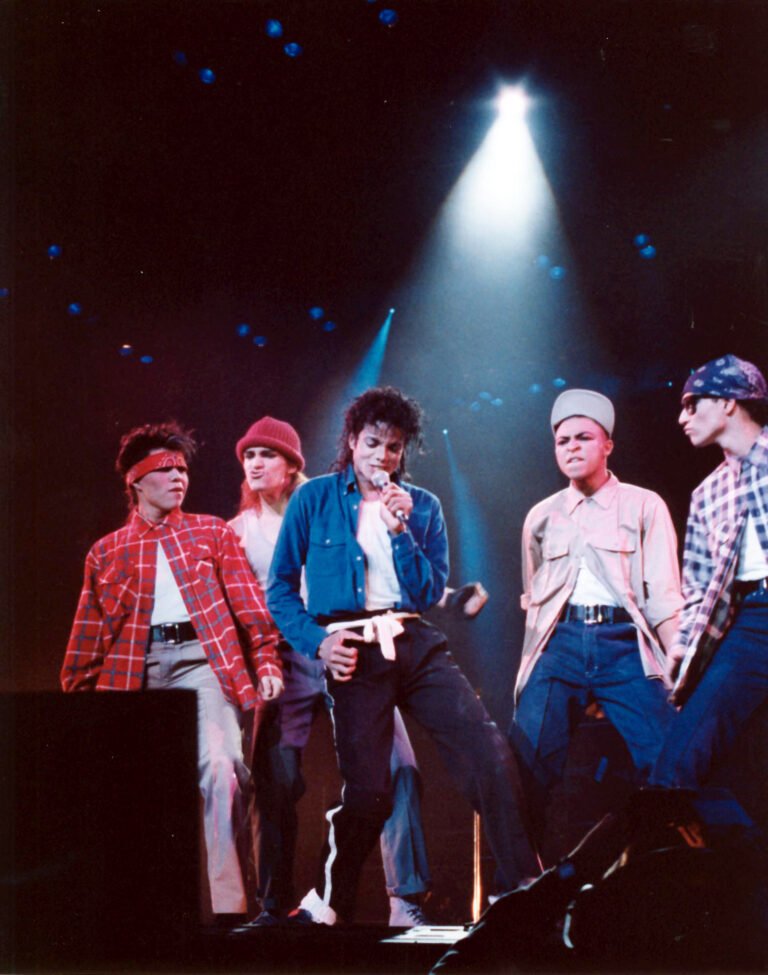 Michael Jackson canta ao microfone com dançarinos ao lado, em fotografia de arquivo de 1988.