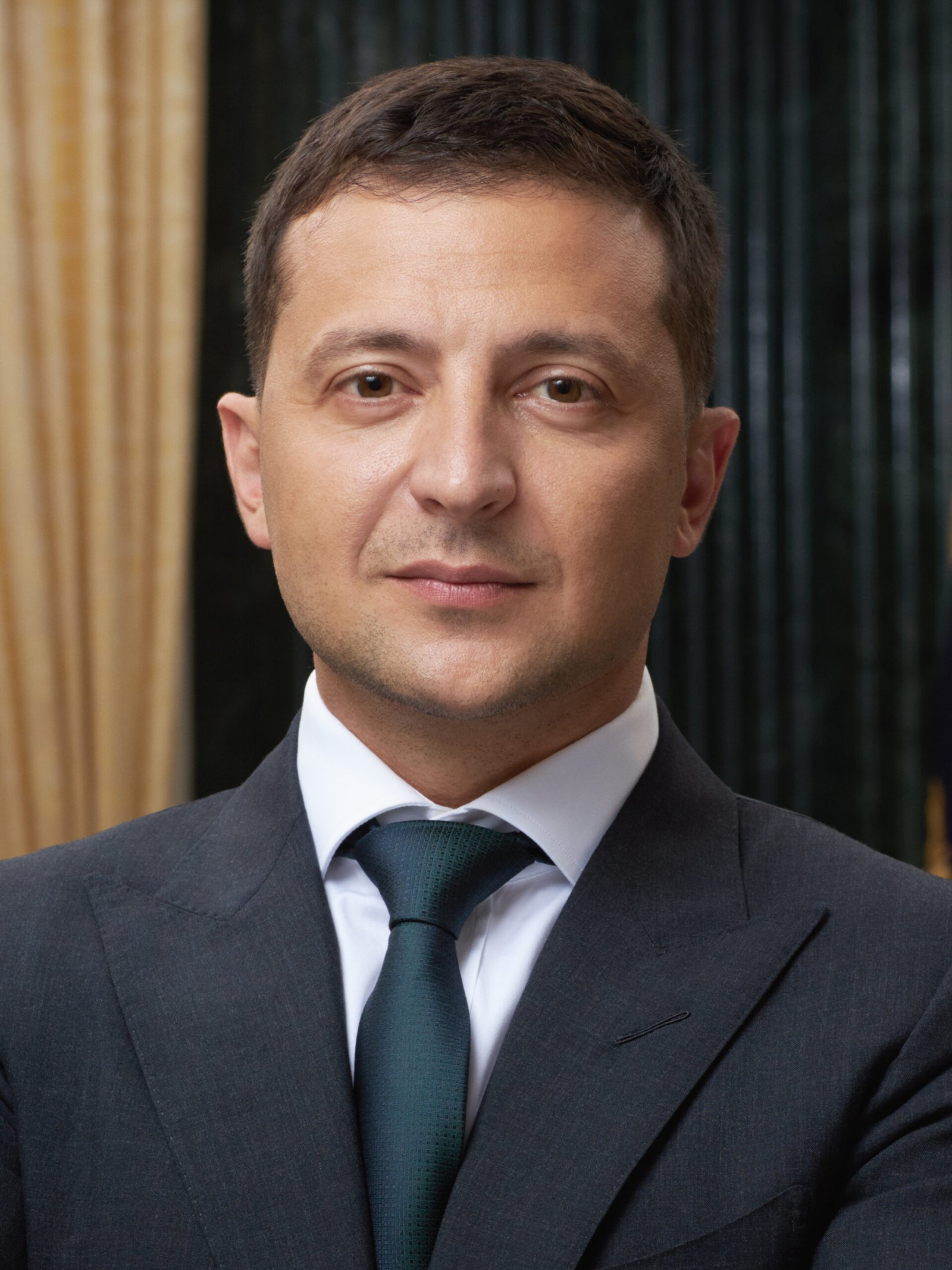Volodymyr Zelensky em retrato oficial de terno escuro e gravata.